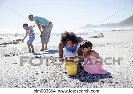 Picture - Mixed race family playing on beach. Fotosearch
