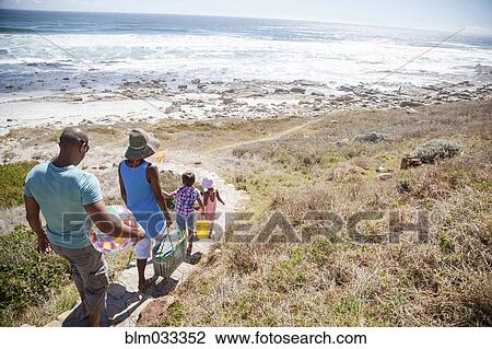 Stock Image - Mixed race family walking on path to beach. Fotosearch