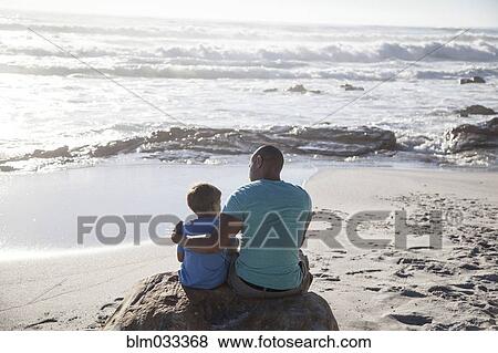 Mixed race father and son sitting on beach View Large Photo Image Stock Photo - Mixed race father and son sitting on beach. Fotosearch