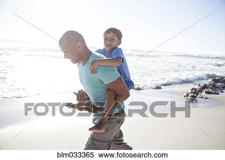 Mixed race father carrying son piggyback on beach View Large Photo Image Stock Photography - Mixed race father carrying son piggyback on beach. Fotosearch