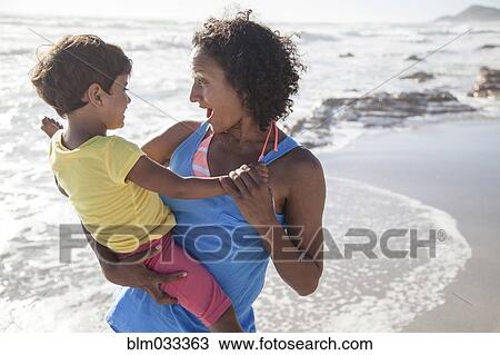 Stock Image - Mixed race mother and daughter playing on beach. Fotosearch