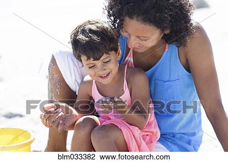 Stock Image - Mixed race mother and daughter playing on beach. Fotosearch