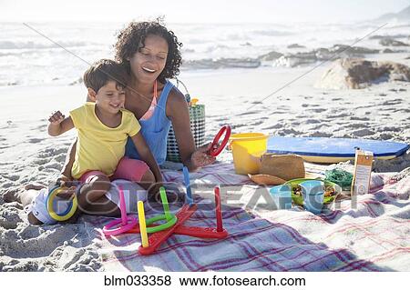 Stock Photo - Mixed race mother and daughter playing at beach. Fotosearch