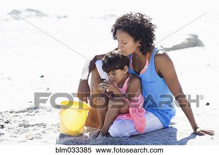 Stock Photography - Mixed race mother and daughter playing on beach. Fotosearch