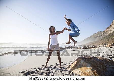 Stock Image - Mixed race mother and son playing on beach. Fotosearch
