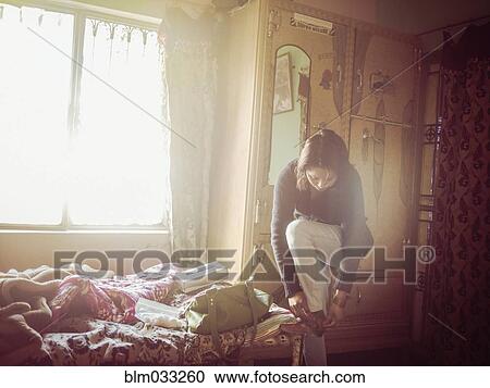 Stock Image - Mixed race woman dressing in bedroom. Fotosearch
