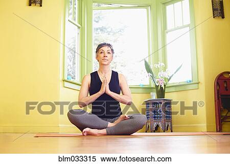 Stock Photography - Older Caucasian woman meditating near window. Fotosearch