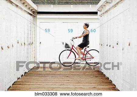 Stock Photo - Older Caucasian woman riding bicycle on wooden dock. Fotosearch