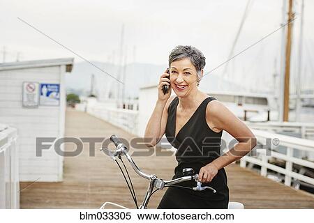 Older Caucasian woman talking on cell phone with bicycle View Large Photo Image Stock Photography - Older Caucasian woman talking on cell phone with bicycle. Fotosearch