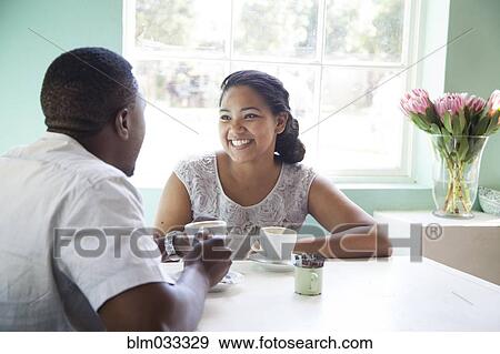 Stock Photo - Smiling couple drinking coffee at table. Fotosearch