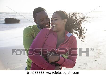Smiling couple hugging on beach View Large Photo Image Stock Photo - Smiling couple hugging on beach. Fotosearch