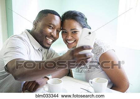 Smiling couple taking cell phone selfie View Large Photo Image Picture - Smiling couple taking cell phone selfie. Fotosearch