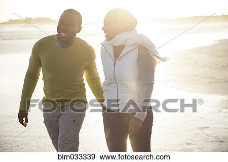 Stock Photo - Smiling couple walking on beach. Fotosearch