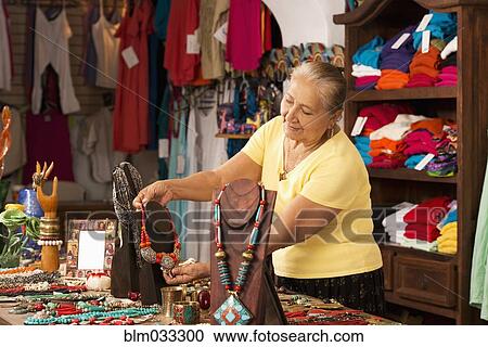 Stock Image - Smiling woman working in traditional gift shop. Fotosearch
