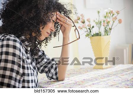 Anxious mixed race woman sitting at table View Large Photo Image Stock Photography - Anxious mixed race woman sitting at table. Fotosearch