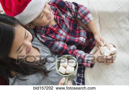 Stock Image - Asian brother and sister drinking hot cocoa at Christmas. Fotosearch