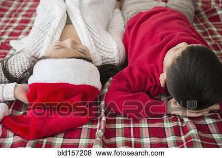 Stock Photo - Asian brother and sister laying on blanket at Christmas. Fotosearch