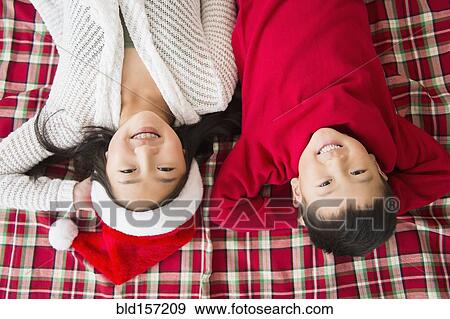 Stock Photo - Asian brother and sister laying on blanket at Christmas. Fotosearch