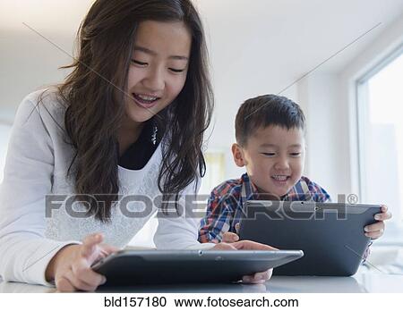 Asian brother and sister using digital tablets at table View Large Photo Image Stock Image - Asian brother and sister using digital tablets at table. Fotosearch
