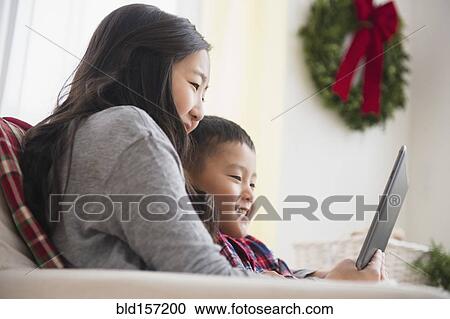 Asian brother and sister using laptop on sofa View Large Photo Image Stock Image - Asian brother and sister using laptop on sofa. Fotosearch