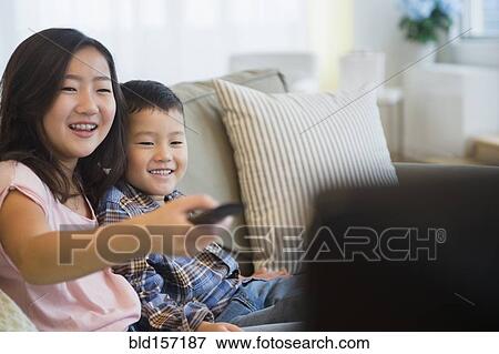 Asian brother and sister watching television on sofa View Large Photo Image Stock Photo - Asian brother and sister watching television on sofa. Fotosearch