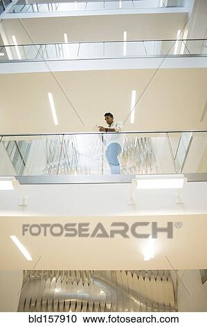 Asian businessman standing on balcony of office building View Large Photo Image Stock Image - Asian businessman standing on balcony of office building. Fotosearch