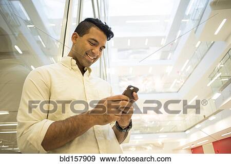 Stock Photo - Asian businessman texting on cell phone. Fotosearch