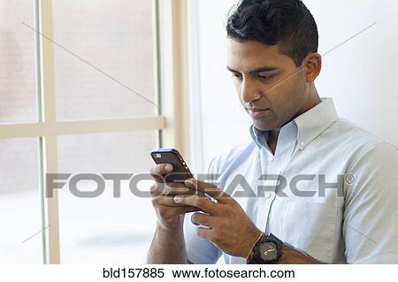 Asian businessman texting on cell phone near window View Large Photo Image Stock Photography - Asian businessman texting on cell phone near window. Fotosearch