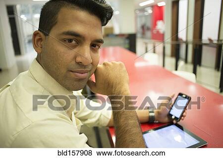 Asian businessman using cell phone and digital tablet in office View Large Photo Image Stock Photo - Asian businessman using cell phone and digital tablet in office. Fotosearch