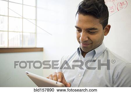 Stock Image - Asian businessman using digital tablet in office. Fotosearch
