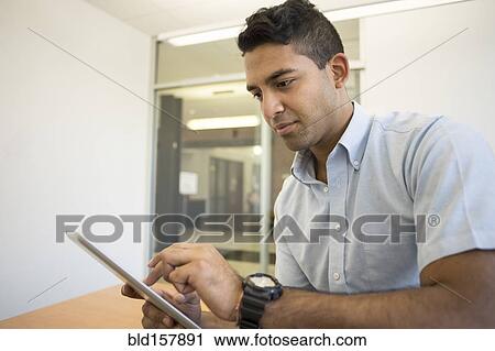 Stock Image - Asian businessman using digital tablet in office. Fotosearch