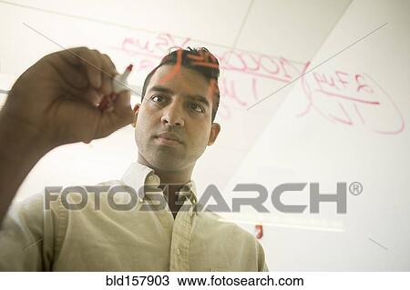 Stock Image - Asian businessman writing formulas on window. Fotosearch