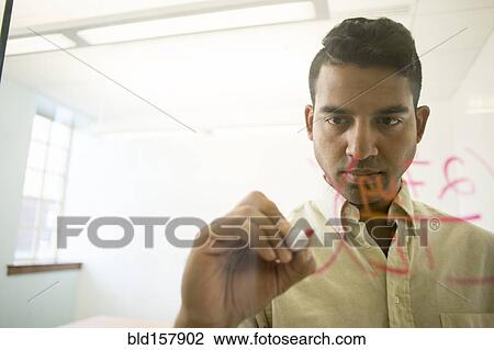Stock Image - Asian businessman writing on glass window in office. Fotosearch