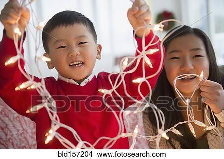 Asian children playing with Christmas string lights View Large Photo Image Picture - Asian children playing with Christmas string lights. Fotosearch