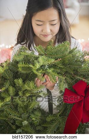 Stock Photograph - Asian girl carrying Christmas wreath. Fotosearch