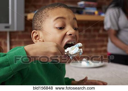 Black boy eating cake at table View Large Photo Image Stock Photo - Black boy eating cake at table. Fotosearch