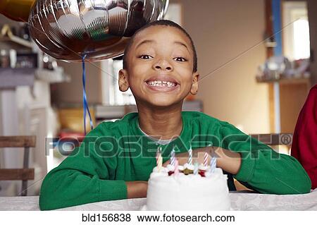 Stock Photo - Black boy smiling with balloon and cake at party. Fotosearch