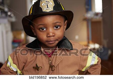 Stock Image - Black boy wearing firefighter Halloween costume. Fotosearch