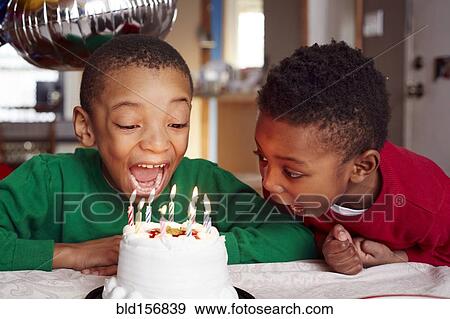 Black boys blowing out cake candles at party View Large Photo Image Stock Photo - Black boys blowing out cake candles at party. Fotosearch