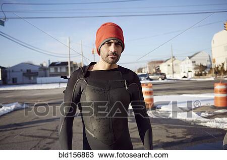 Stock Image - Black man in wetsuit standing in snow. Fotosearch