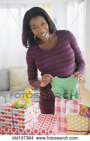 Black pregnant woman admiring gifts at baby shower View Large Photo Image Picture - Black pregnant woman admiring gifts at baby shower. Fotosearch