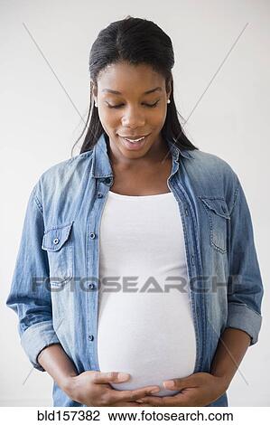 Stock Image - Black pregnant woman admiring her stomach. Fotosearch