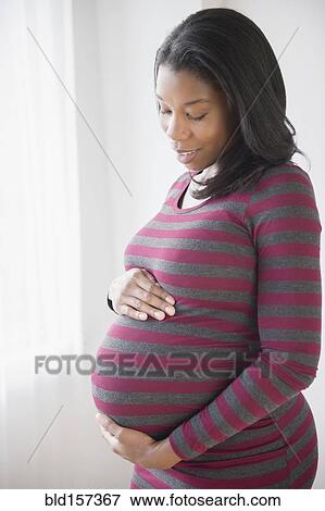Black pregnant woman admiring her stomach View Large Photo Image Stock Photo - Black pregnant woman admiring her stomach. Fotosearch