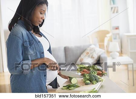 Black pregnant woman chopping vegetables in kitchen View Large Photo Image Stock Image - Black pregnant woman chopping vegetables in kitchen. Fotosearch