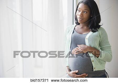 Black pregnant woman holding her stomach at window View Large Photo Image Stock Image - Black pregnant woman holding her stomach at window. Fotosearch
