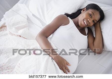 Black pregnant woman smiling in bed View Large Photo Image Stock Photo - Black pregnant woman smiling in bed. Fotosearch