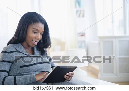 Black pregnant woman using digital tablet on sofa View Large Photo Image Stock Image - Black pregnant woman using digital tablet on sofa. Fotosearch