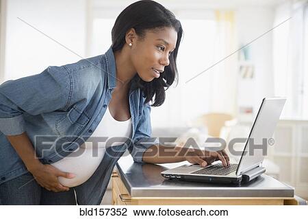Black pregnant woman using laptop in kitchen View Large Photo Image Stock Image - Black pregnant woman using laptop in kitchen. Fotosearch