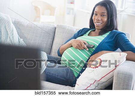 Black pregnant woman watching television on sofa View Large Photo Image Stock Photography - Black pregnant woman watching television on sofa. Fotosearch