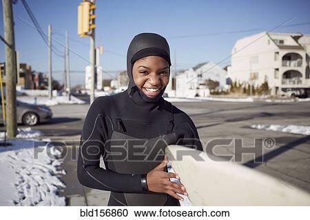 Black teenage girl in wetsuit carrying surfboard in winter View Large Photo Image Stock Image - Black teenage girl in wetsuit carrying surfboard in winter. Fotosearch